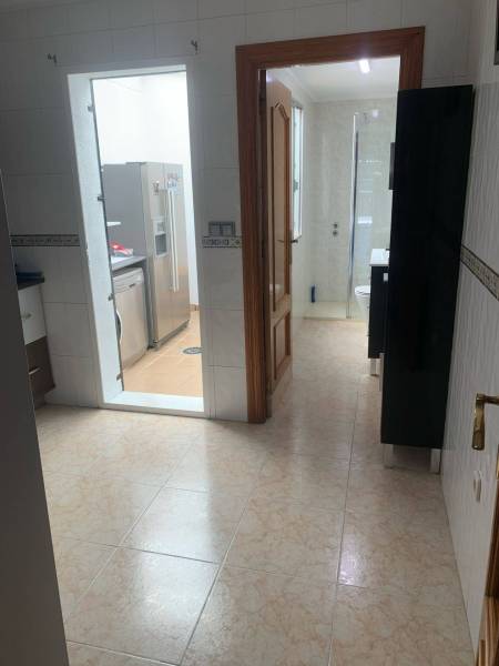 Hallway with entrance to the bathroom and kitchen in a family house, light tiles.