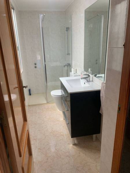 Bathroom in a family house with a sink, shower, and light-colored tiles.