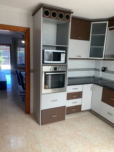 A kitchen in a family house with a microwave, an oven, and glass cabinet doors.
