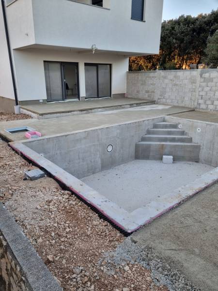 4-bedroom apartment with an unfinished pool in Mandre, terrace, and partially fenced plot.