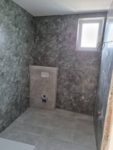 A bathroom with gray tiles and a window in a 4-room apartment.