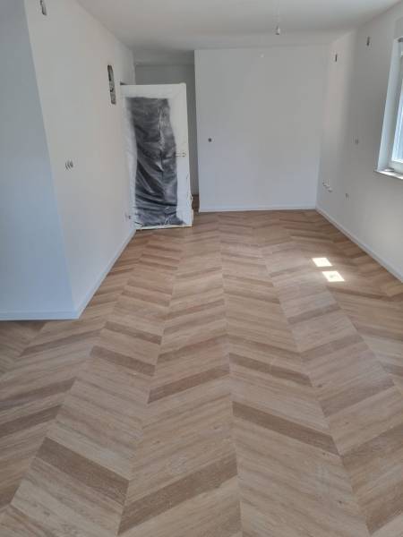 Interior of a 4-room apartment with new wooden flooring and lighting from the window.