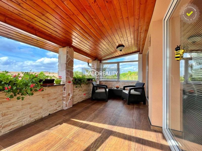 A glazed terrace with a wooden ceiling and flowers in a family house.