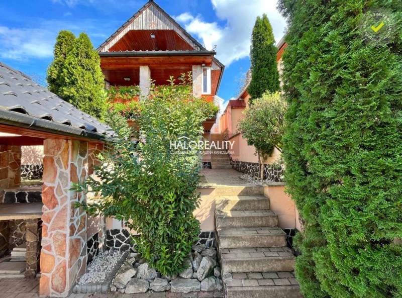 A family house in Levice surrounded by greenery and flowers with stone details.