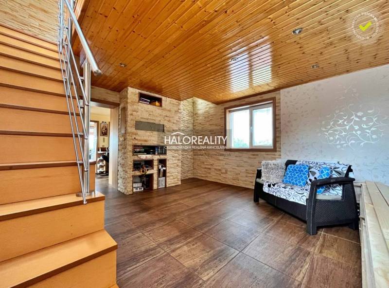The interior of a family house with a wooden ceiling, staircase, and sofa set.