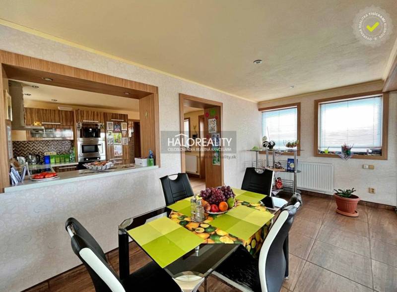 Dining room in a family house with a black table, chairs, and a view of the kitchen.