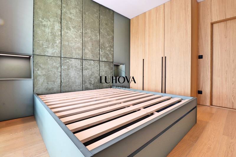 Bedroom with a bed with a slatted frame, wooden floor, and built-in wardrobe in a 2-room apartment.