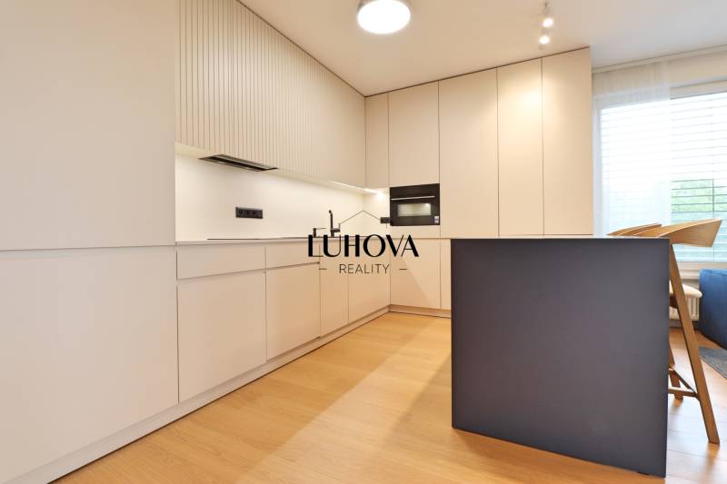 A kitchen in a 2-room apartment with white cabinets and seating at the counter.