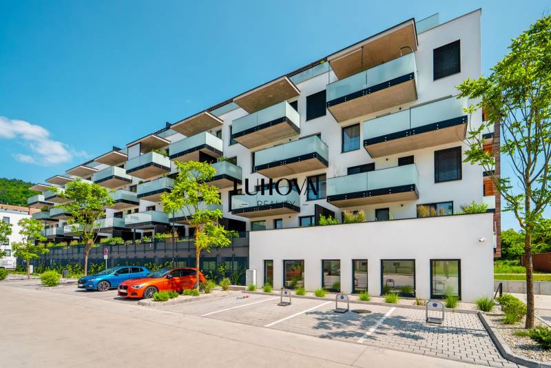 Residential building on Dlhé lúky in Púchov with a parking lot and greenery in front of the building.