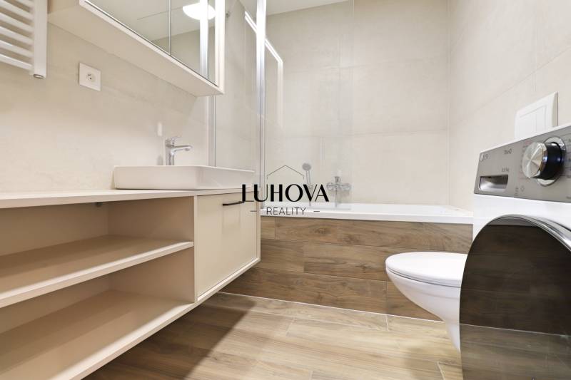 A bathroom with a bathtub and a washing machine in a 2-room apartment.