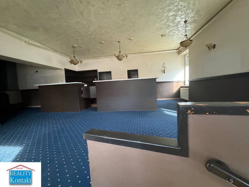 Interior of commercial spaces with carpets and a counter, illuminated by pendant lamps.