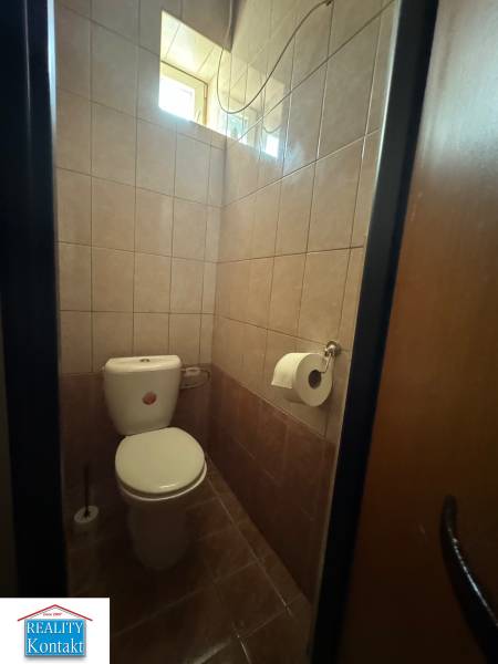 A restroom with tiled walls in commercial premises, with a window for natural light.