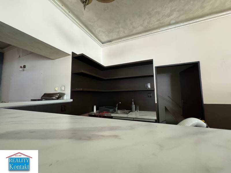 A kitchen unit with shelves and a sink in commercial premises, with doors leading to a room.