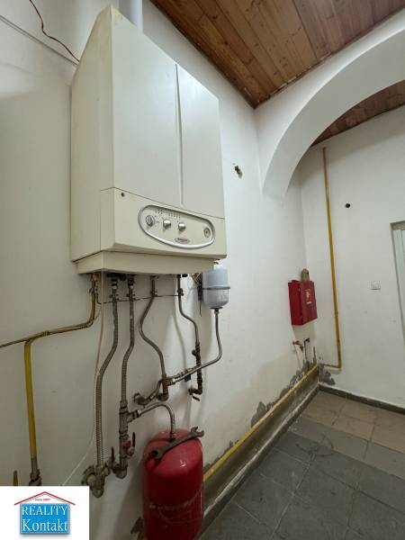 Kettle and piping in commercial premises, wall with slight signs of wear.