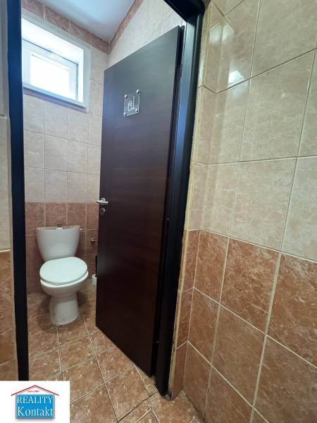 A restroom with closed doors in commercial premises, tiled with brown tiles.