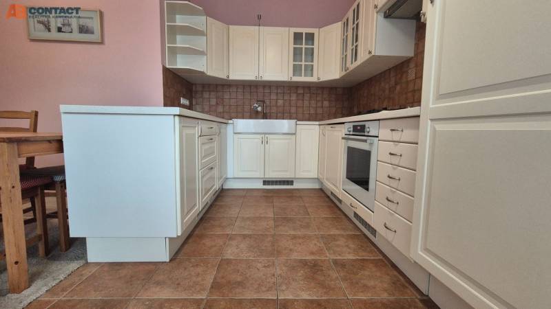 A kitchen in a 5 or more room apartment with white cabinets and brown tiles.