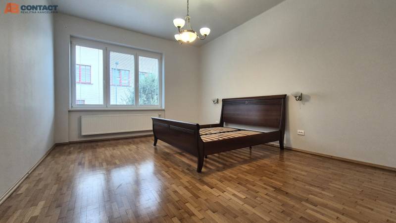 A room in a 5 or more bedroom apartment with a bed and wooden floor.