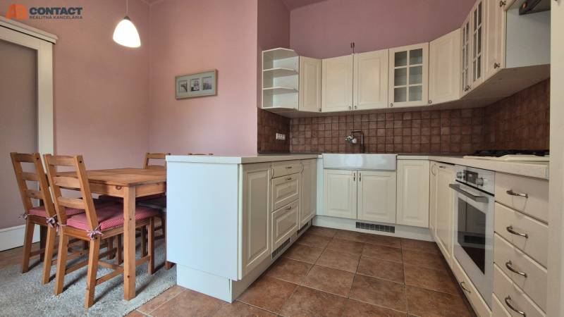 A kitchen with a wooden table and chairs in a five or more room apartment.