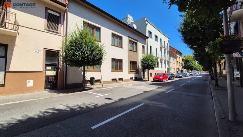 A street in Piešťany with apartment buildings and parked cars.