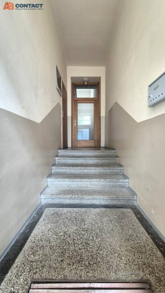 A hallway with a staircase leading to wooden doors in a 5 or more room apartment.
