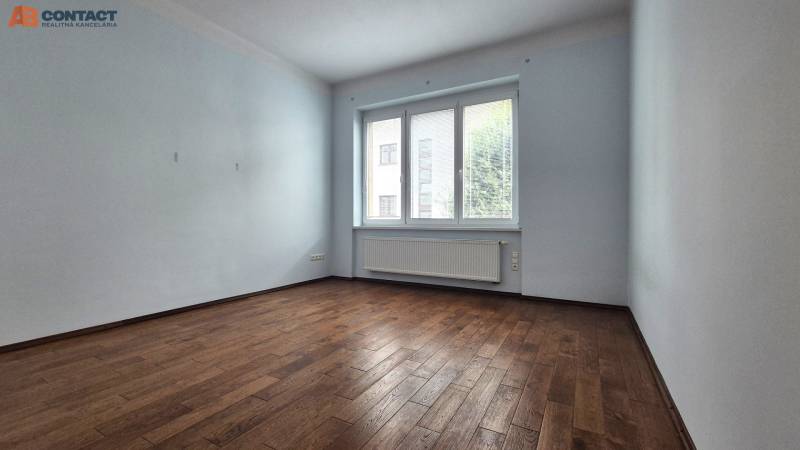 A spacious room with wooden flooring and a large window in a 5 or more room apartment.