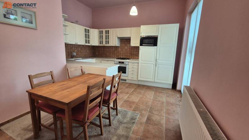 A kitchenette with a dining table, cabinets, and appliances in a 5 or more room apartment.