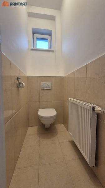 A toilet with tiles, a window, and a radiator in a 5 or more room apartment.