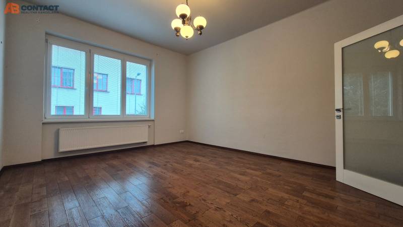 A spacious room with wooden flooring and a large window in a 5 or more room apartment.