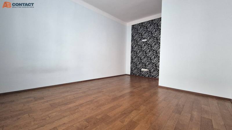 An empty room with a wooden floor and a decorative wall in a multi-room apartment.