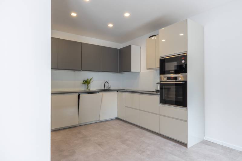 A kitchen in a family house with minimalist white-gray cabinets and built-in appliances.