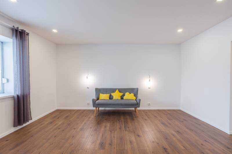Gray sofa with yellow cushions in the living room of a family house, wooden floor.