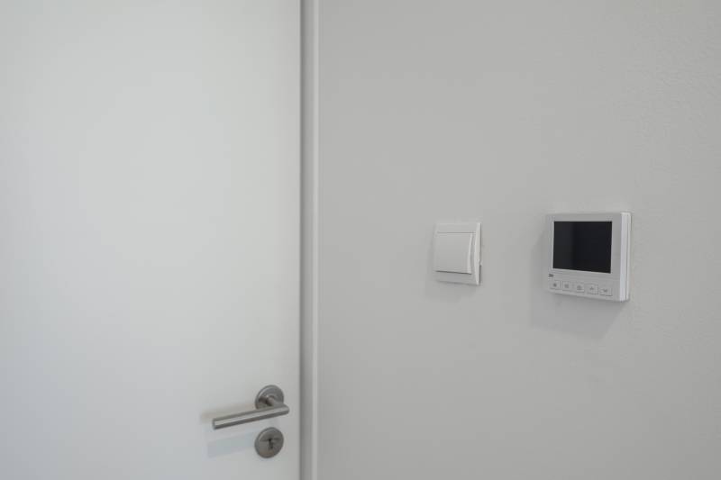 Door with a metal handle, switch, and control panel in a family house.