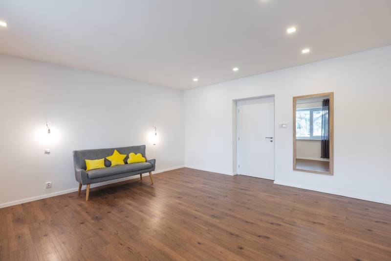 A family house with a wooden floor, a sofa, and decorative pillows.