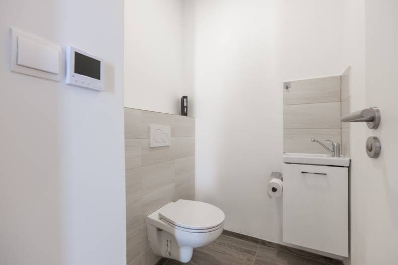 A toilet and sink in a family house with white walls and light tiles.