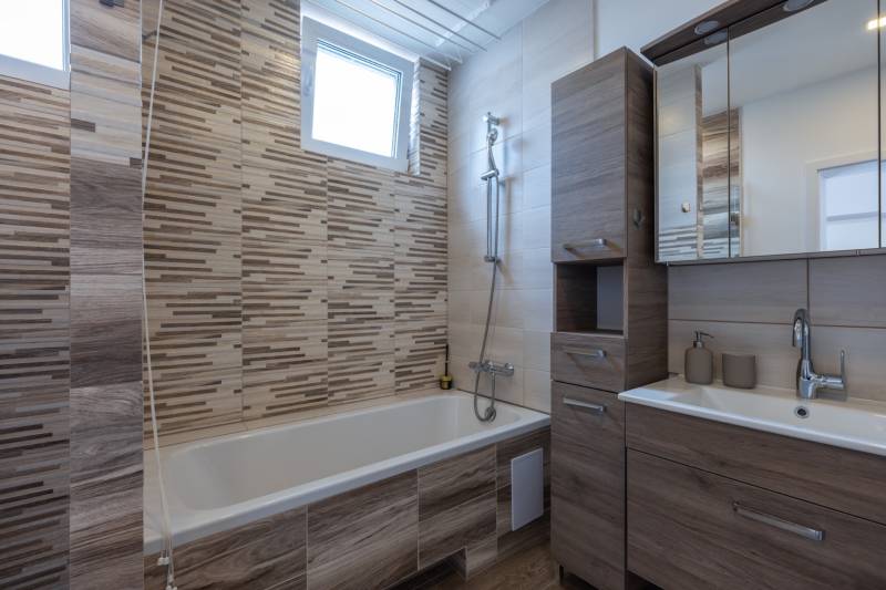 Bathroom with a bathtub, wooden furniture, and a sink in a family house.