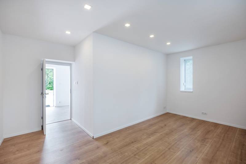 An empty room in a family house with wooden flooring and white walls.