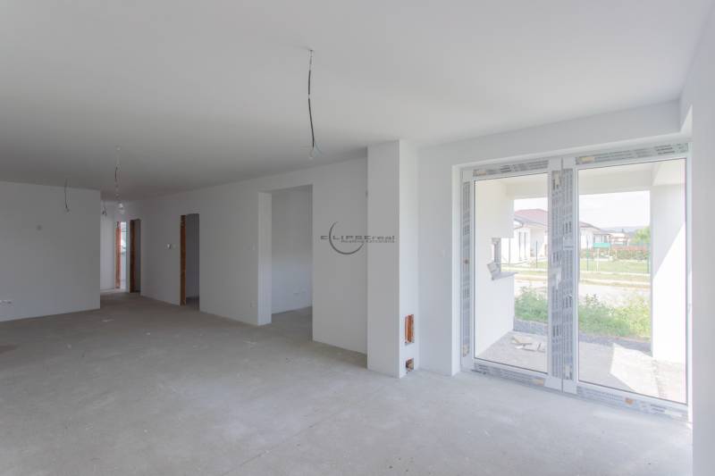 The interior of a family house with an unfinished floor and large windows.
