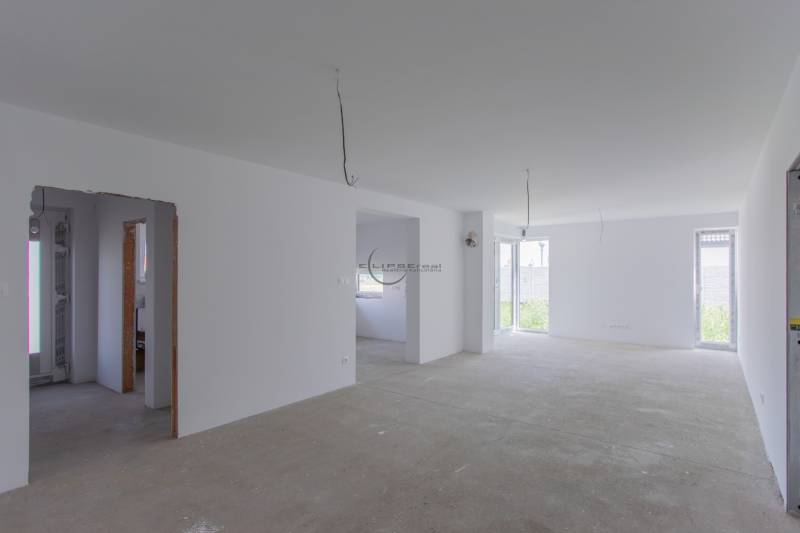 A spacious, bright room with windows in a family house and incomplete ceiling electrical installations.