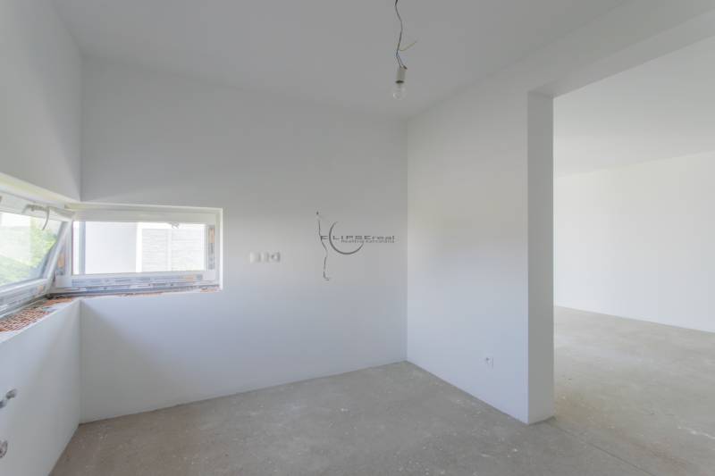 A bright room in a family house with a gray floor and a window.