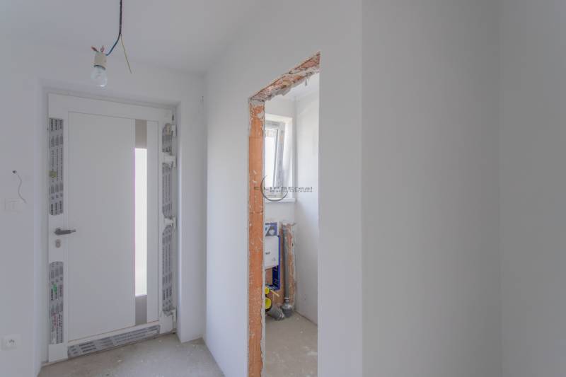The interior of a family house with white walls, lighting, and an uncovered construction opening.