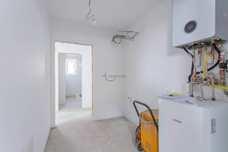Technical room in a family house with heating equipment and visible cables.