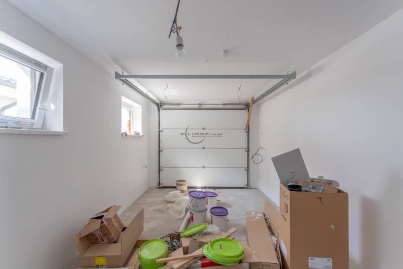 Unorganized garage in a family house, cardboard boxes, buckets, light walls.