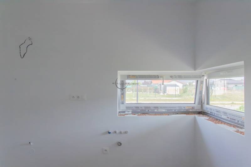 Unbuilt kitchen in a family house with drawers and a window.