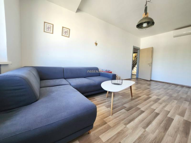 Living room with a blue sofa, table, and wooden floor in a 2-room apartment.