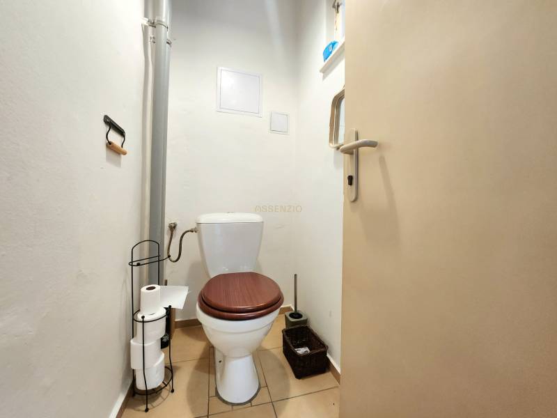 Bathroom in a 2-room apartment, with a toilet and a toilet paper holder.