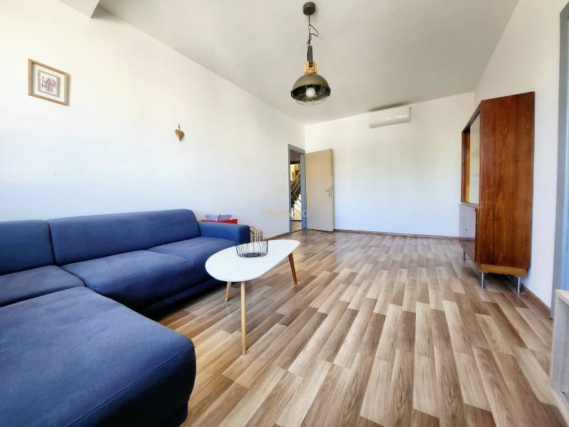 Living room with a blue sofa, wooden floor, and minimalist furniture in a 2-room apartment.