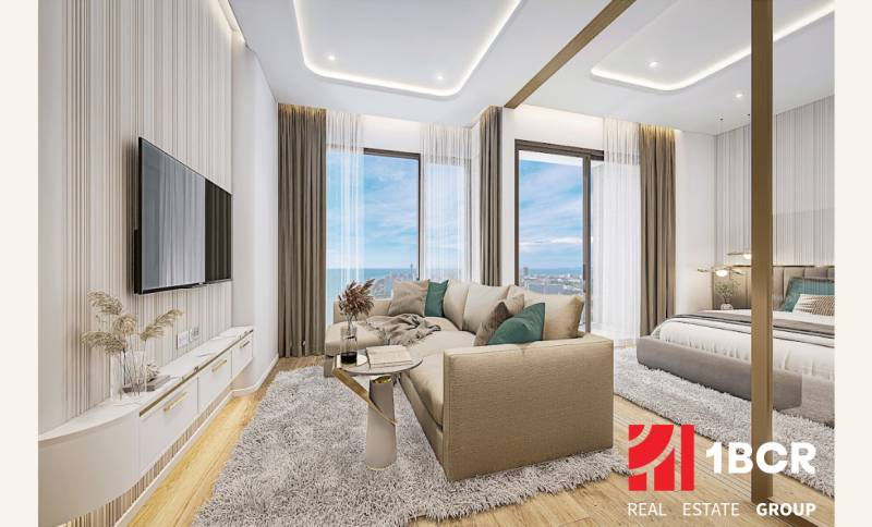 Living room of a 2-room apartment with a sea view, featuring a comfortable couch and a television.