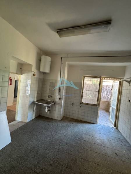 Interior of commercial premises with a sink, tiles, and glass doors.