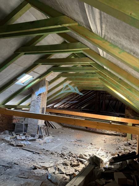 The ceiling of commercial premises with a wooden structure and building materials scattered on the floor.