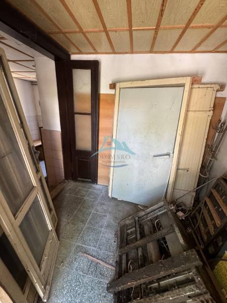 A narrow corridor in commercial premises with debris and old doors.